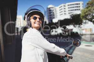 Smiling businesswoman sitting on motor scooter