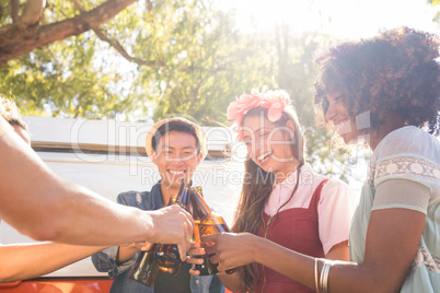 Smiling friends toasting beer bottles