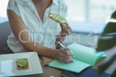 Midsection of businesswoman having food