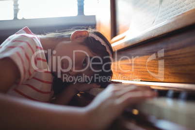 Portrait of girl leaning on piano in classroom