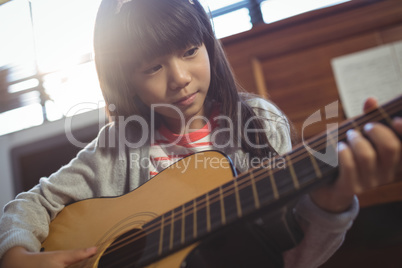 Concentrated girl practicing guitar