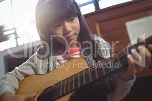 Concentrated girl practicing guitar