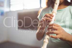 Mid section of girl playing flute in classroom