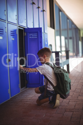 Side view of boy taking books from locker