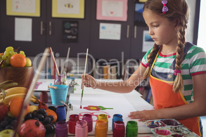 Concentrated girl painting at desk