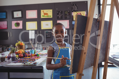 Portrait of smiling girl painting on canvas