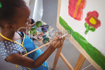 High angle view of elementary girl painting on canvas
