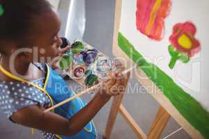 High angle view of elementary girl painting on canvas