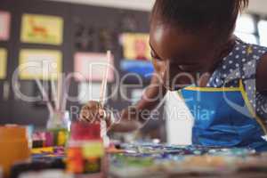 Concentrated elementary girl painting at desk