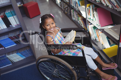 Portrait of smiling girl with book on wheelchair