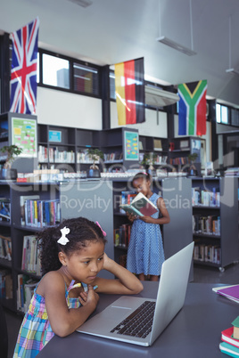 Concentrated girl looking at laptop in library