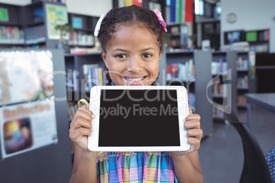 Smiling girl showing digital tablet in library