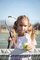 Portrait of girl holding racket and tennis ball