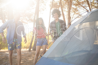 Happy friends standing by tent