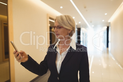 Businesswoman using phone in corridor