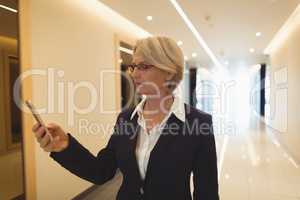 Businesswoman using phone in corridor