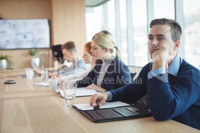 Thoughtful businessman sitting with colleagues working in office