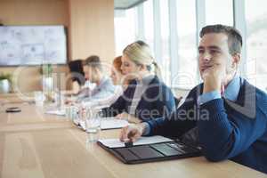 Thoughtful businessman sitting with colleagues working in office