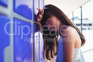 Portrait of sad girl leaning on lockers