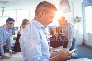 Businessman using mobile phone with team in background