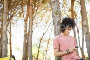 Young man using mobile phone at forest
