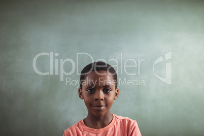 Smiling boy against blank greenboard