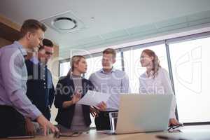 Classy business colleagues discussing around desk