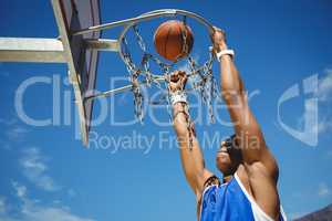 Low angle view of teenager hanging on basketball hoop