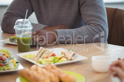 Mid section of businessman sitting at office cafeteria