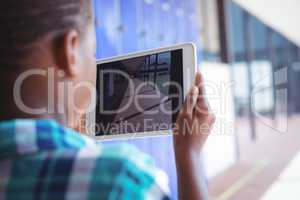 Schoolboy photographing corridor through digital tablet at school