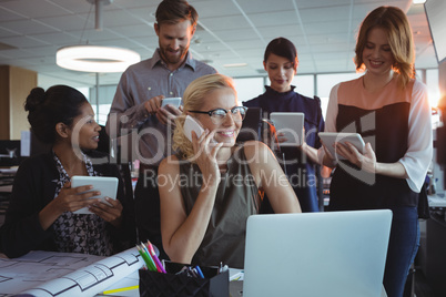 Smiling business colleagues using mobile phones and digital tablets together