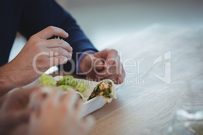 Hands of business colleagues having breakfast at office cafeteria