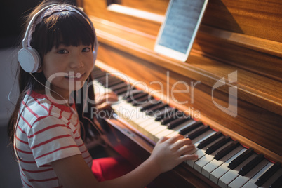 High angle portrait of girl wearing headphones while practicing piano