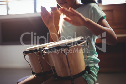 Mid section of girl playing bongo drums