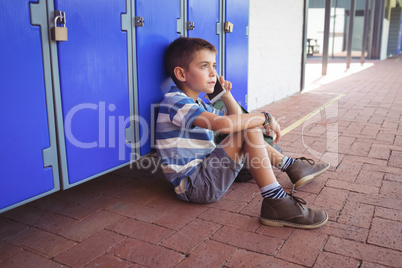 High angle view of boy talking on mobile phone while sitting by lockers