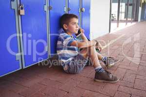 High angle view of boy talking on mobile phone while sitting by lockers