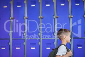 Boy carrying backpack against lockers