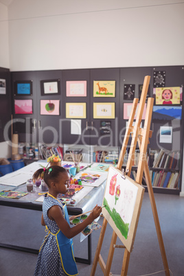 High angle side view of girl painting on canvas