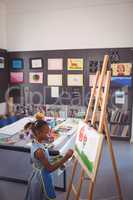 High angle side view of girl painting on canvas