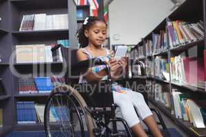 Girl using digital tablet on wheelchair in library