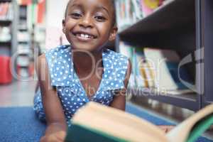 Portrait of smiling girl with book in library