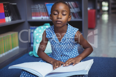 Girl reading braille book in library
