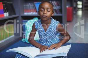 Girl reading braille book in library