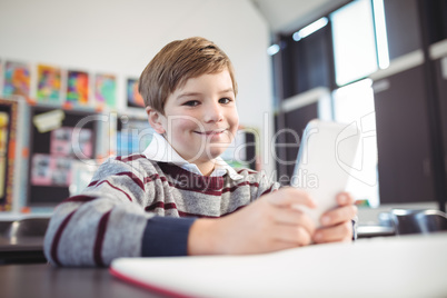 Smiling boy using mobile phone at desk