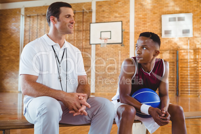 Smiling coach guiding basketball player