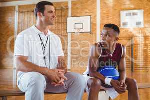 Smiling coach guiding basketball player