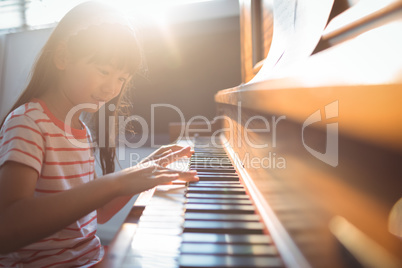 Smiling girl practicing piano in classroom