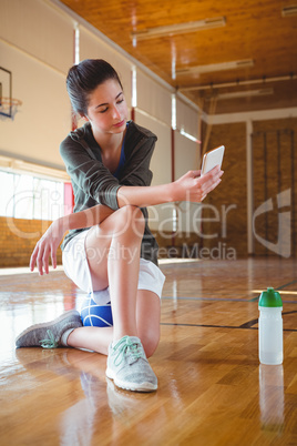 Full length of female basketball player using mobile phone