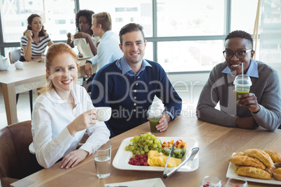 Portrait of smiling business colleagues sitting at breakfast table