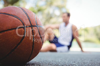 Close up of orange basketball with player sitting in background